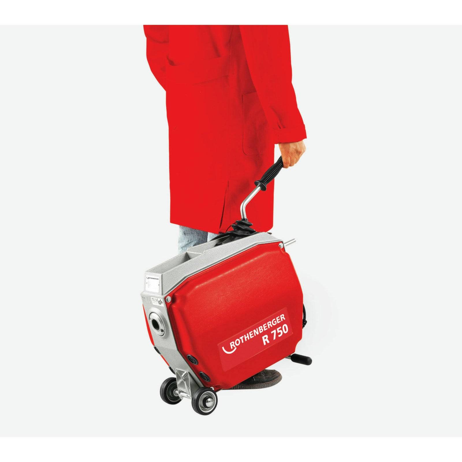 Eine Person in einem roten Mantel zieht ein rotes Rothenberger R 750 Gerät auf Rädern, höchstwahrscheinlich für industrielle oder Bauanwendungen.