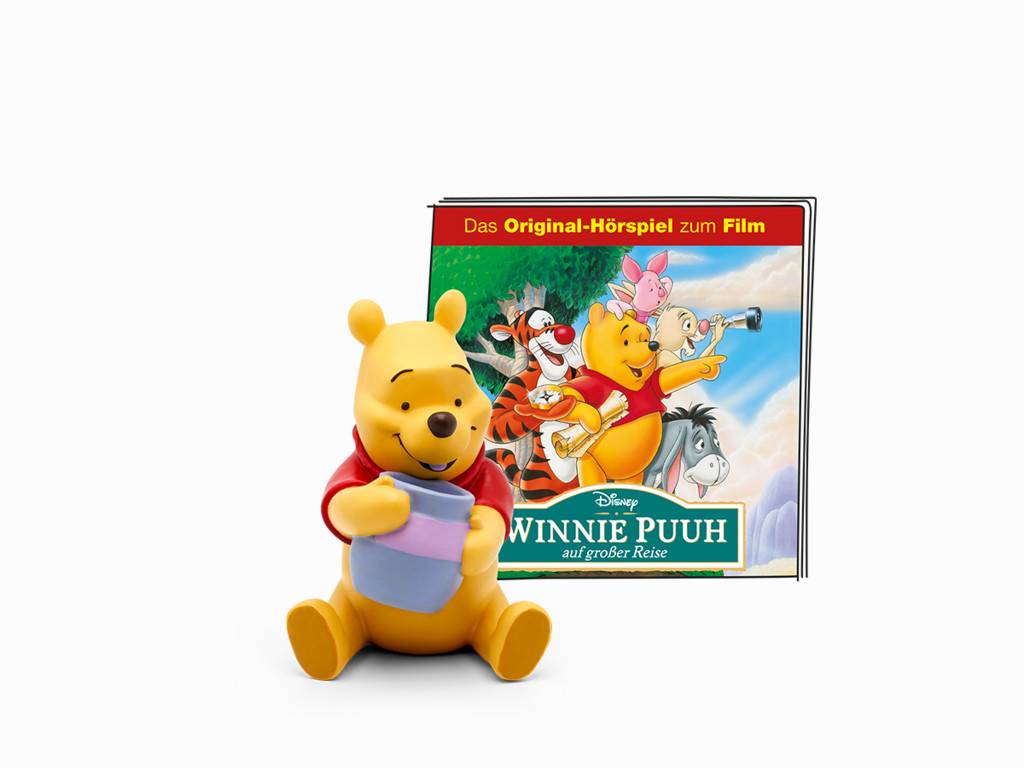 Winnie-der-Bär-Figur, die einen Behälter hält, vor einem Hörbuch-Cover mit dem Titel „Winnie Puuh auf großer Reise