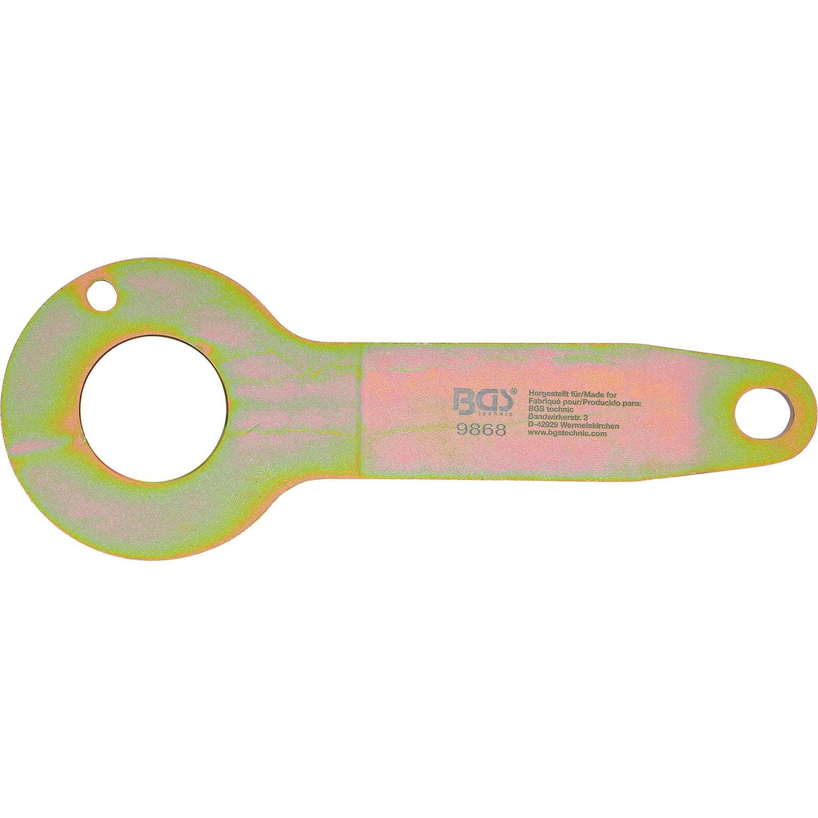 Ein metallisches Werkzeug mit zwei Löchern und gravierten Buchstaben, das für spezifische Einstellungen in der Automechanik verwendet wird.