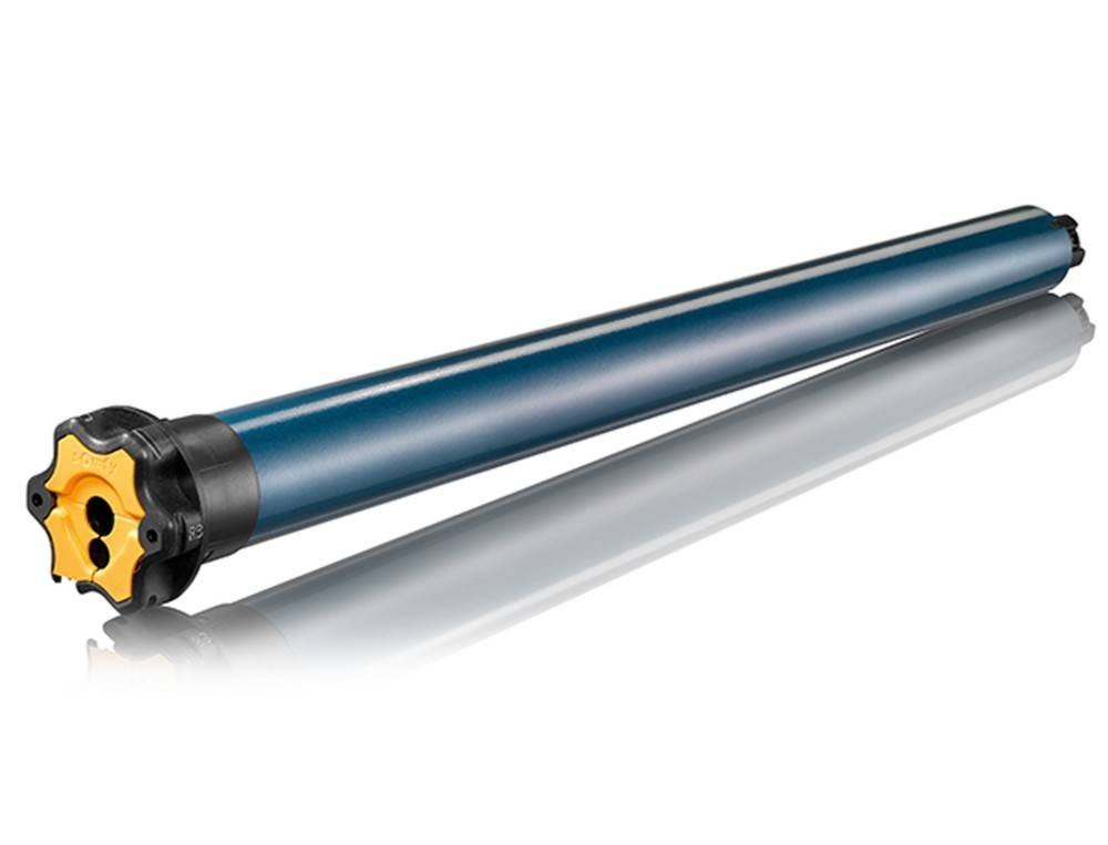 Eine zylindrische Metallröhre, blau mit einem schwarz-gelben Enddeckel, liegt horizontal und spiegelt sich auf einer weißen Oberfläche.