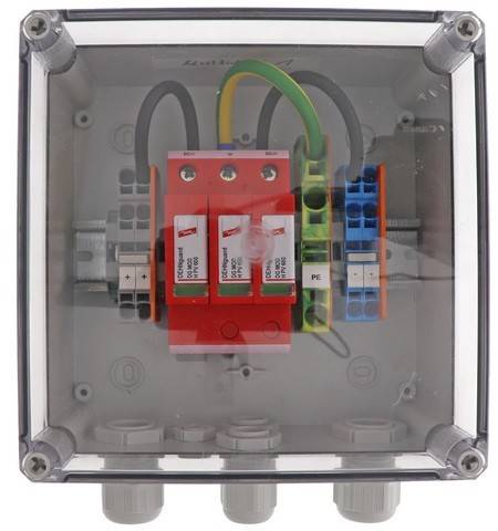 Elektrische Verteilerdose mit roten und blauen Leitungsverbindern, Überspannungsschutzgerät und beschrifteter Schaltung in einem transparenten Gehäuse.