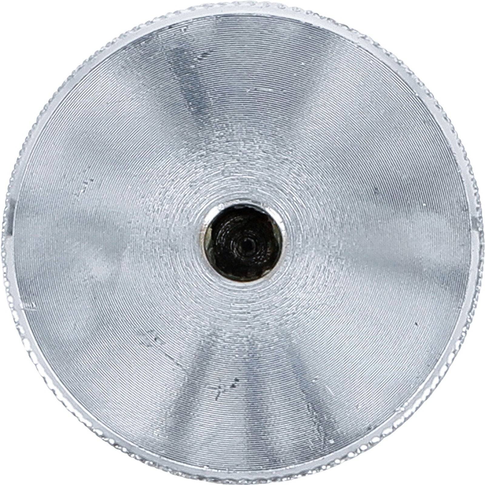 Ein kreisförmiger, metallischer Gegenstand mit einem zentralen dunklen Fleck. Der Gegenstand weist konzentrische Rillen auf, die ihm eine strukturierte, reflektierende Oberfläche verleihen.