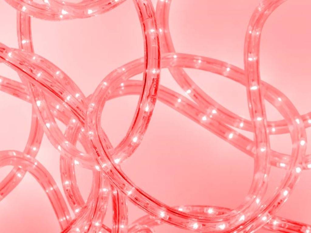 Ein Gewirr von leuchtenden rosafarbenen LED-Lichtstreifen bildet Schleifen und Kurven und erzeugt ein abstraktes Muster vor einem sanften rosa Hintergrund.