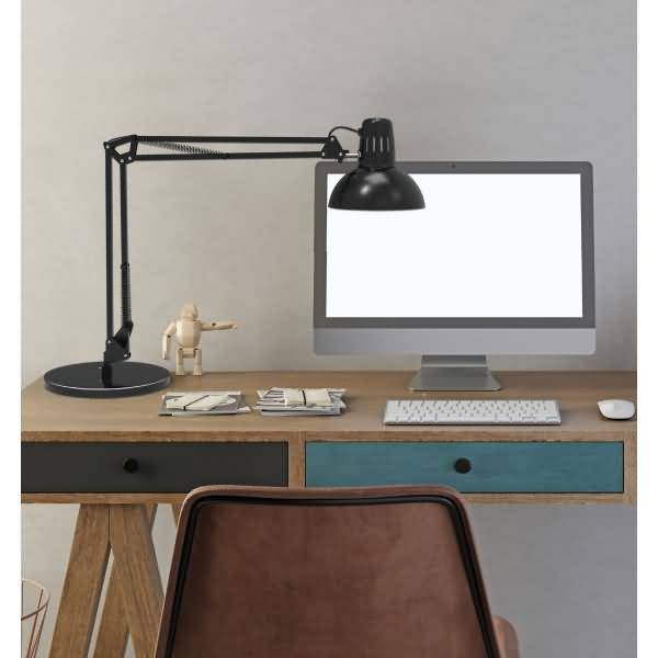 Minimalistischer Home-Office-Schreibtisch mit leerem Desktop-Monitor, Lampe, Tastatur, Maus und gestapelten Papieren; leerer Stuhl im Vordergrund.