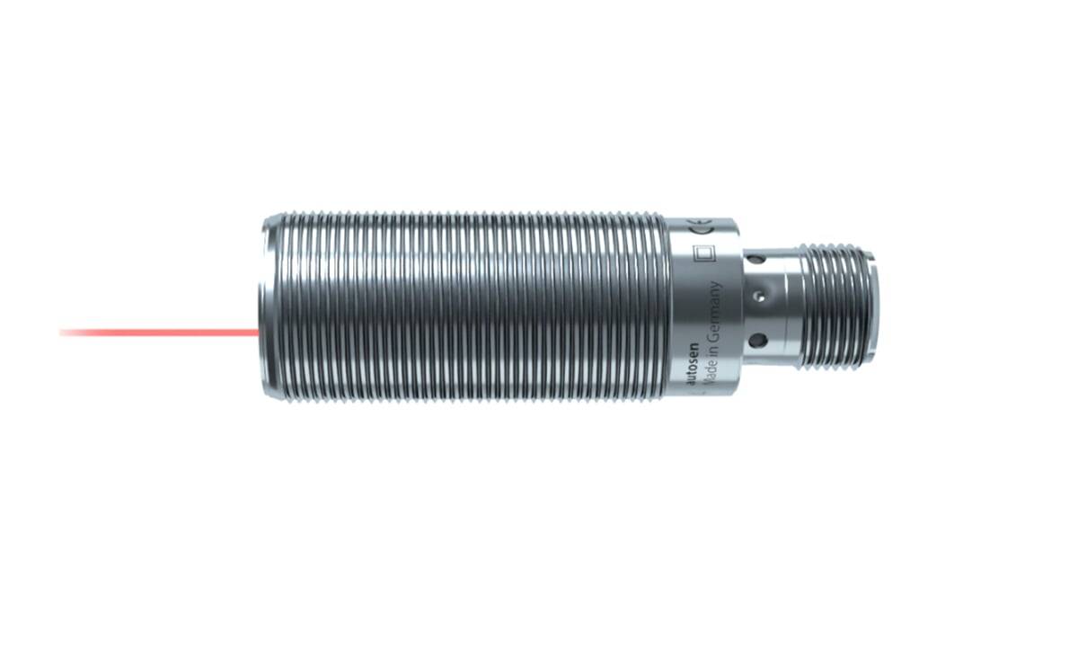 Ein zylindrischer, metallischer Sensor sendet einen roten Laser von einem Ende aus. Er trägt eingravierte Schriftzüge, die darauf hinweisen, dass er in Deutschland hergestellt wurde.