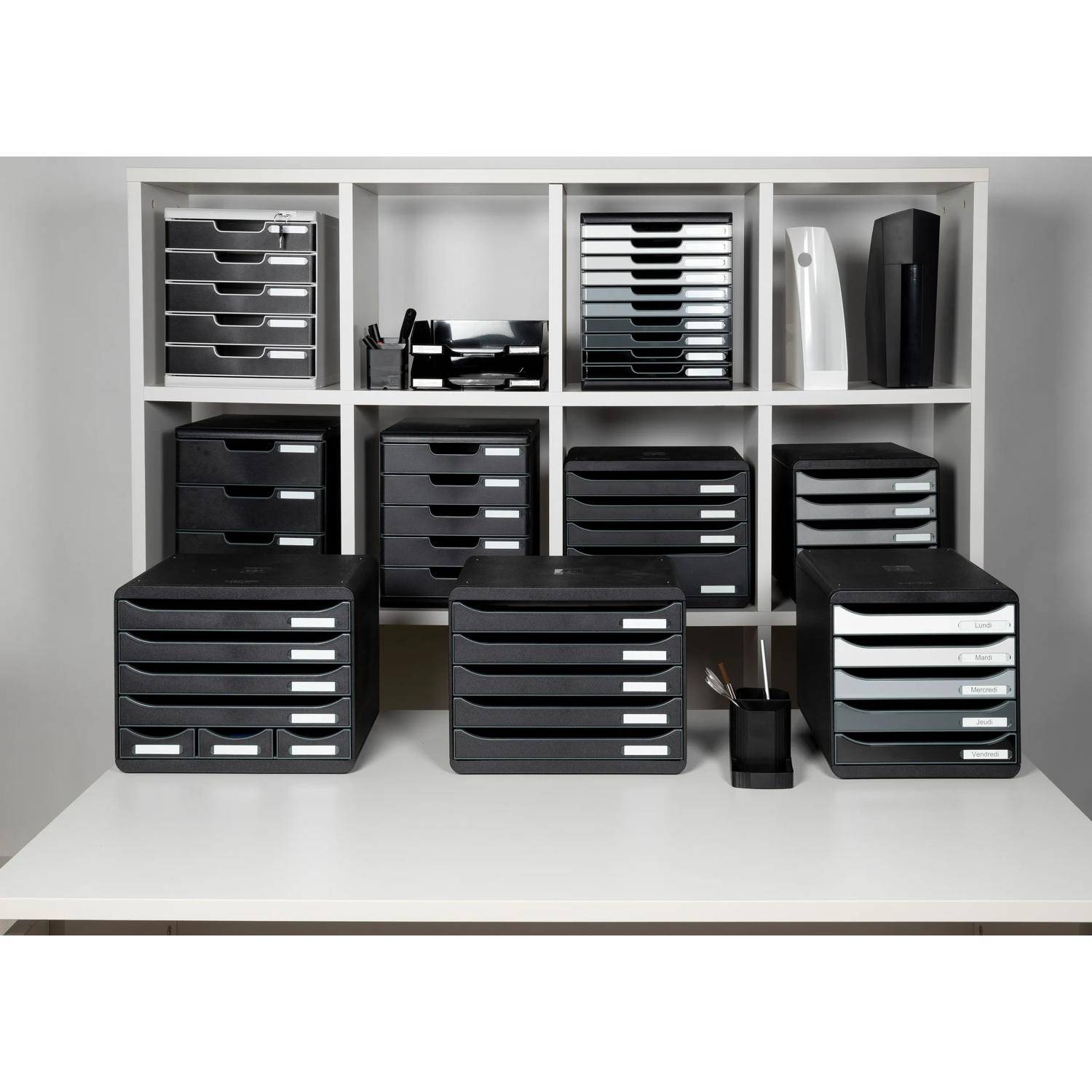 Assortierte schwarze und weiße Schreibtischorganizer und Ablageboxen, die auf weißen Regalen und einer Tischplatte angeordnet sind.