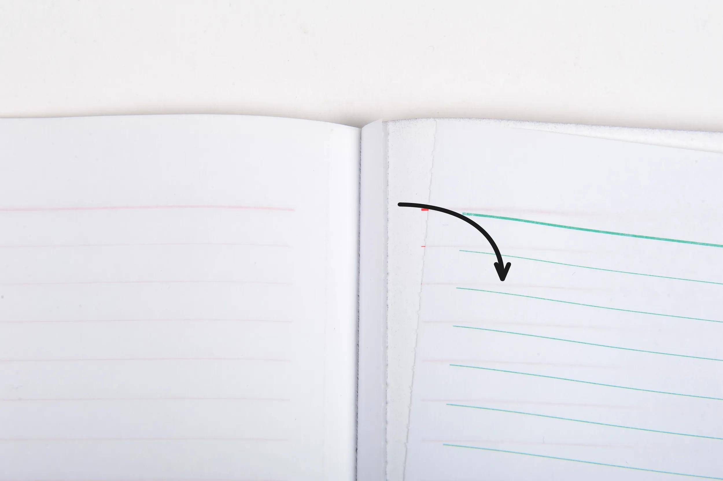 Ein offenes Notizbuch mit einer leichten Biegung in den Seiten, das liniertes Papier in Rot und Blau zeigt, mit einem dunklen Pfeil, der von oben links nach rechts Mitte zeigt.