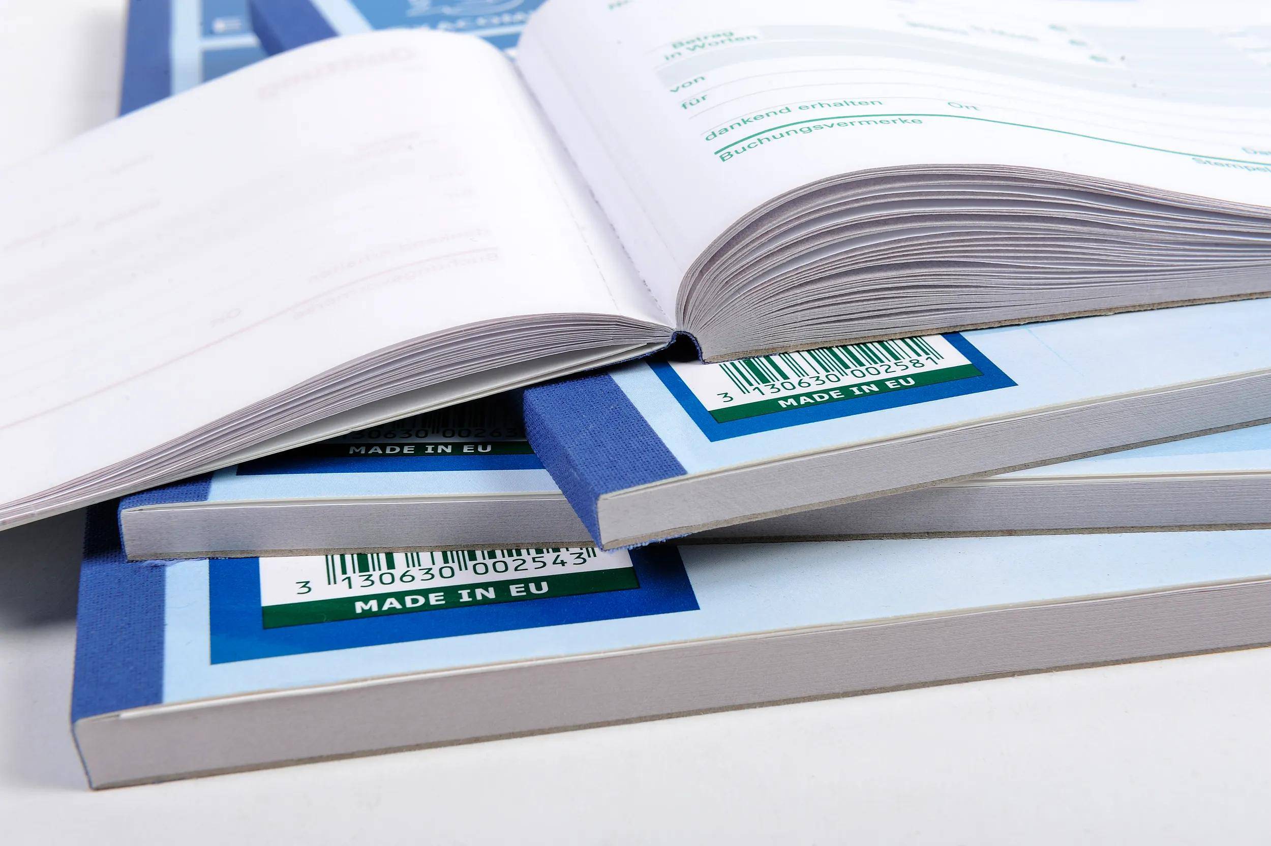 Aufgeschlagene Bücher, die auf einem Tisch gestapelt sind und Seiten zeigen, mit 