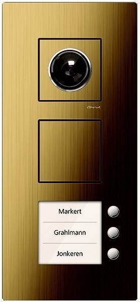 Ein goldener Türsprechanlage-Panel mit einer Kamera oben, einem rechteckigen Knopf und einem weißen Namensschild unten mit der Aufschrift ‚Markert'.