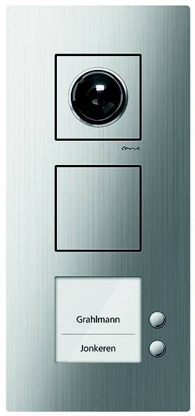 Ein Metallpanel mit drei rechteckigen Abschnitten in vertikaler Anordnung; der obere Abschnitt weist ein kreisförmiges schwarzes Objekt mit einer Linse auf.