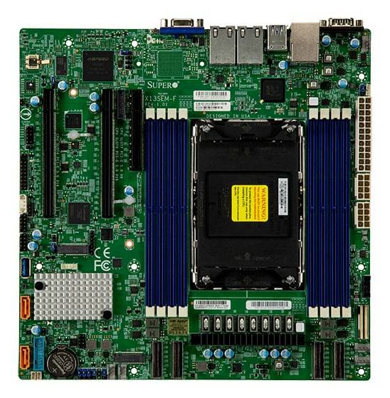 Computerplatine mit einer zentralen Prozessorsockel und vier blauen RAM-Steckplätzen, von oben auf einer grünen Leiterplatte gezeigt.