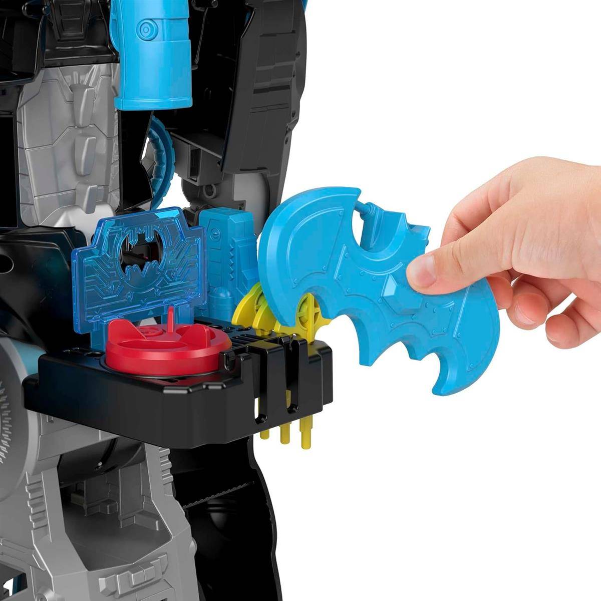 Hand führt ein blaues Batman-förmiges Spielzeugstück in einen Schlitz eines Batman-Design-Spielsets ein, wobei andere Spielzeugteile sichtbar sind.