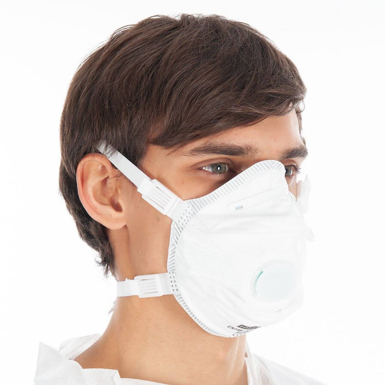 Junger Mann, der eine weiße Schutzgesichtsmaske vor einem weißen Hintergrund trägt.