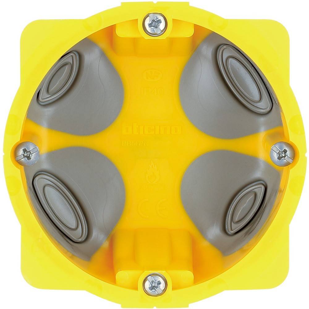 Eine gelbe elektrische Verteilerbox mit vier kreisförmigen grauen Einsätzen und sichtbaren Schraubenbefestigungen an den Ecken.