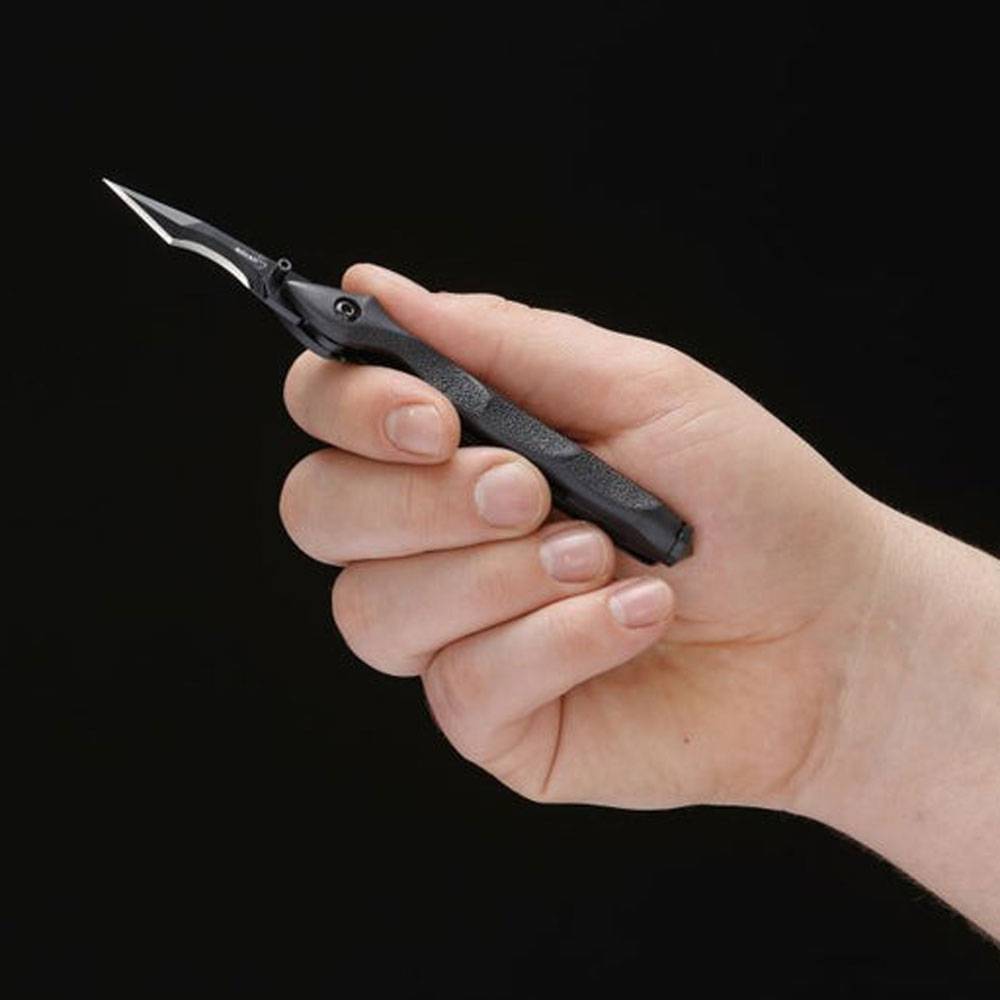 Eine Hand hält ein kleines schwarzes Universalmesser mit einer spitzen Klinge vor einem schlichten dunklen Hintergrund.