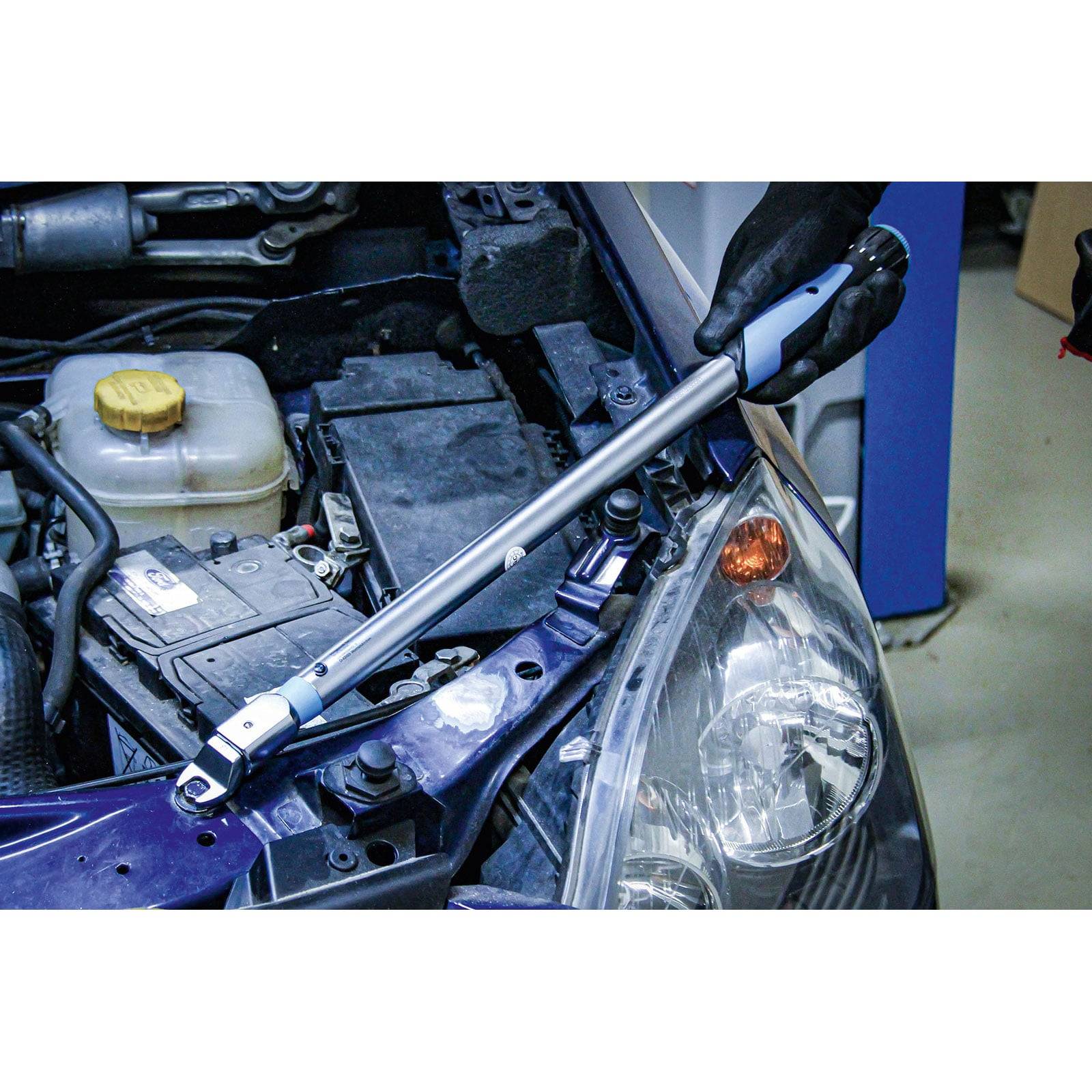 „Ein Drehmomentschlüssel wird im vorderen Bereich eines Fahrzeugmotors, in der Nähe der Batterie und des Scheinwerfers, in einer Garage verwendet.