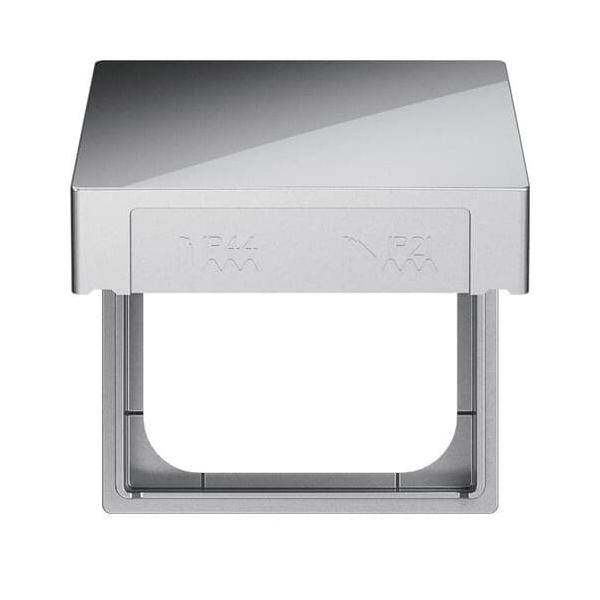 Eine metallische Steckdosenabdeckung ist geöffnet und gibt eine einzelne Steckdose darunter frei. Das Design ist schlicht und modern, aus silberfarbenem Material gefertigt.