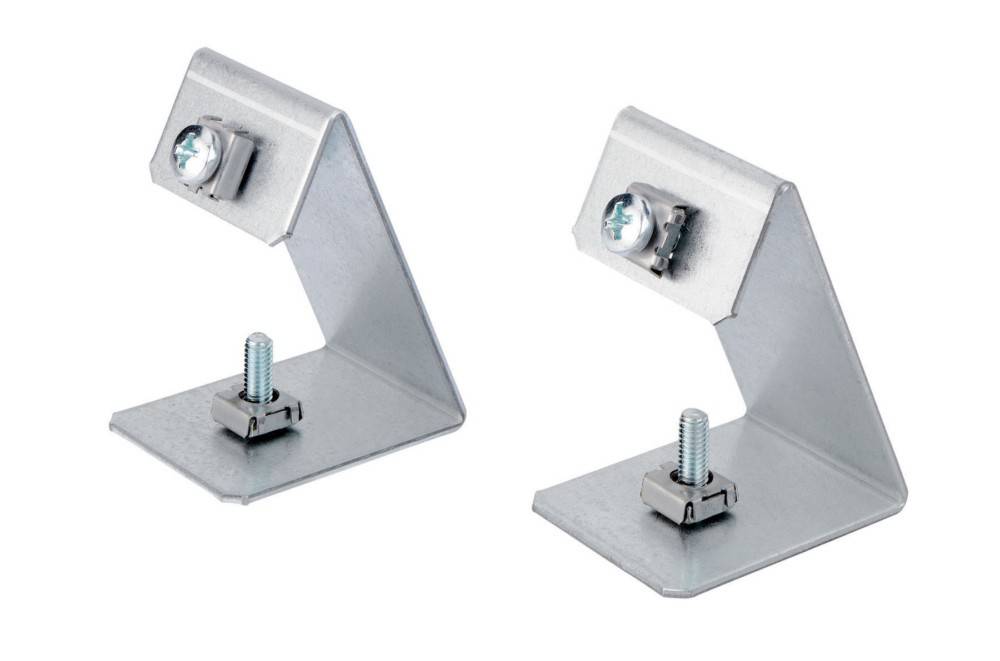 Zwei Metallhalterungen mit Schrauben, die auf ebenen Flächen positioniert sind. Jede Halterung hat ein rechtwinkliges Design, das vertikale und horizontale Ebenen verbindet.