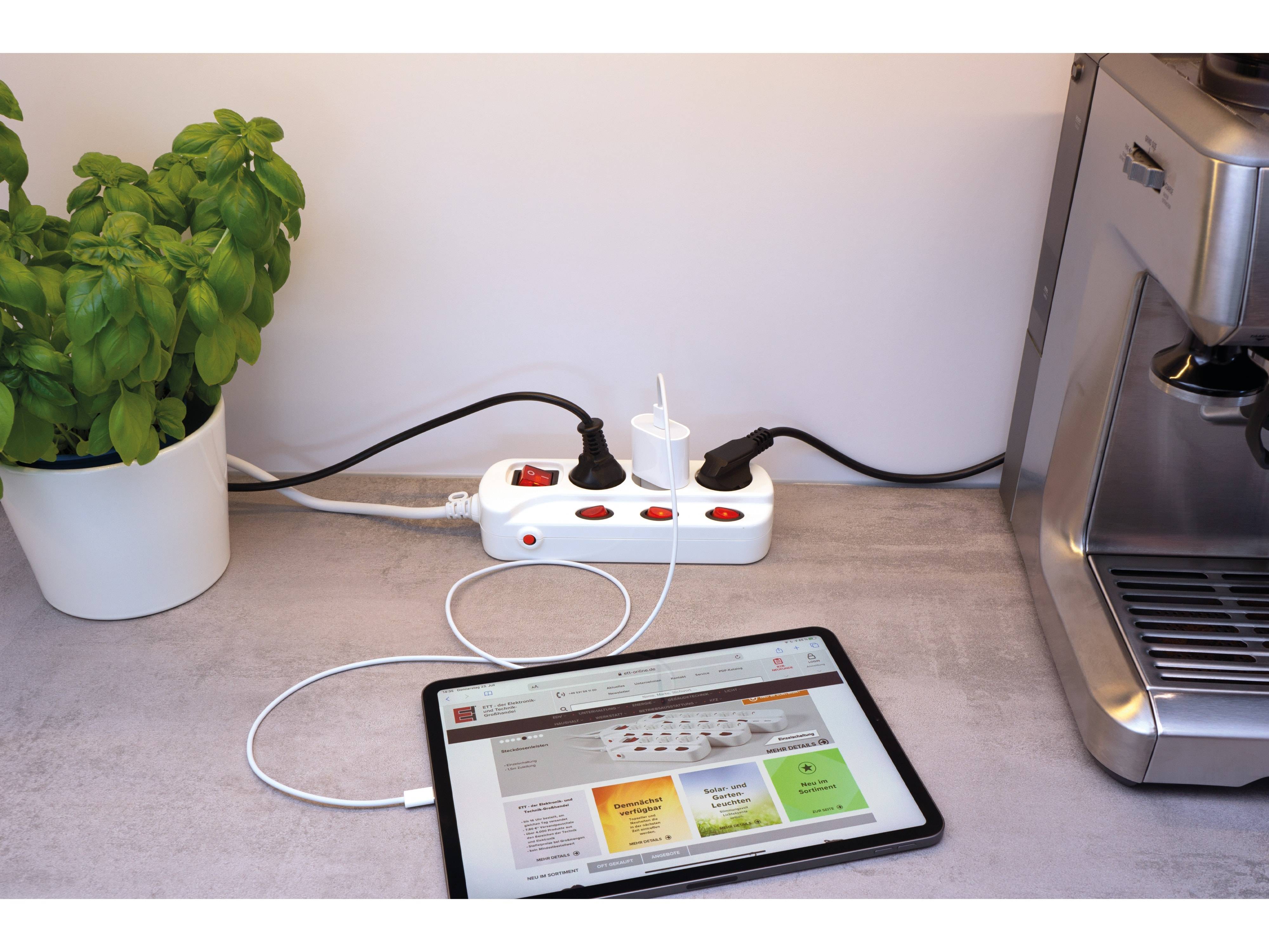 Ein Tablet, das eine Website anzeigt, steht auf einer Theke und ist mit einer Steckdosenleiste verbunden. In der Nähe befindet sich eine Topfpflanze.