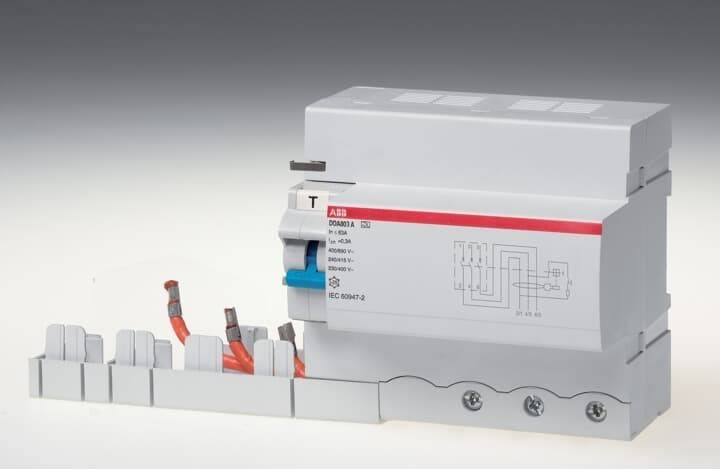 Ein weißer und grauer elektrischer Sicherungsautomat von ABB mit roten und blauen Schaltern ist auf einer Metallschiene mit angeschlossenen Kabeln montiert.