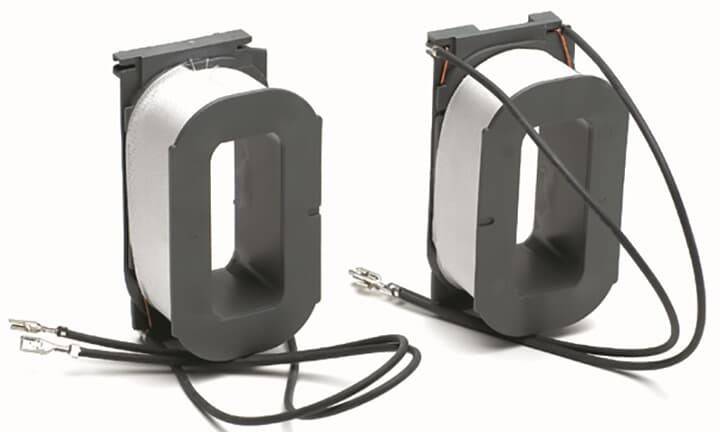Zwei große, rechteckige Stromwandler aus Metallspulen mit schwarzen Kabeln und Metallverbindern, die zur Messung elektrischer Ströme verwendet werden.