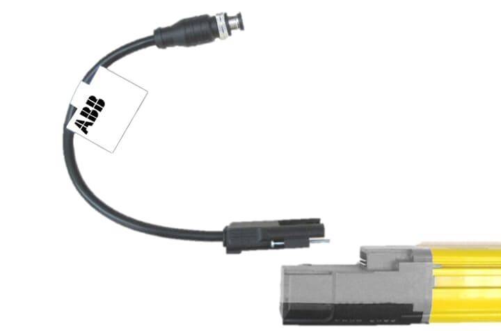 Ein schwarzes Kabel mit einem BNC-Stecker und einer kleinen Karte, die an einem Ende befestigt ist, verbunden mit einer rechteckigen grauen elektronischen Komponente.