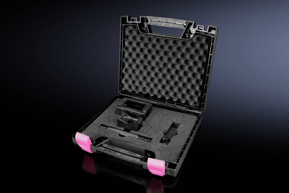 Eine schwarze, mit Schaumstoff gepolsterte Tasche mit rosa Verschlüssen, geöffnet, zeigt verschiedene Fächer und liegt auf einer glänzend schwarzen Oberfläche.