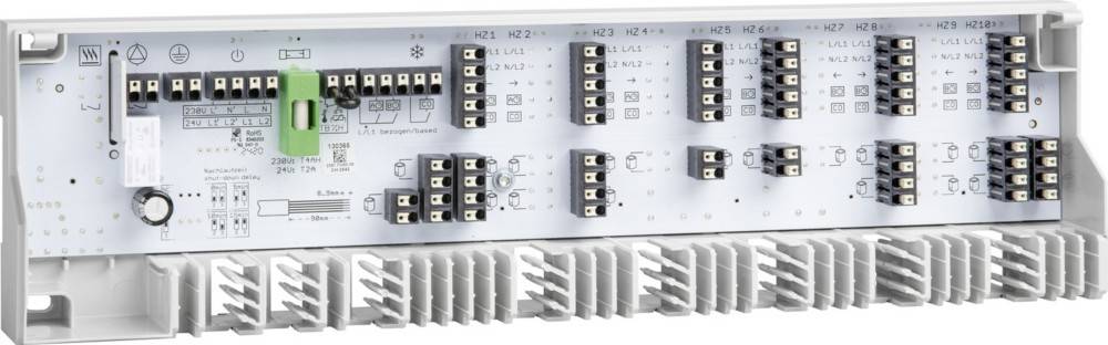 Ein weißes elektrisches Schaltpanel mit mehreren schwarzen Schaltern und beschrifteten Anschlüssen, das zur Steuerung und Verteilung elektrischer Stromkreise verwendet wird.