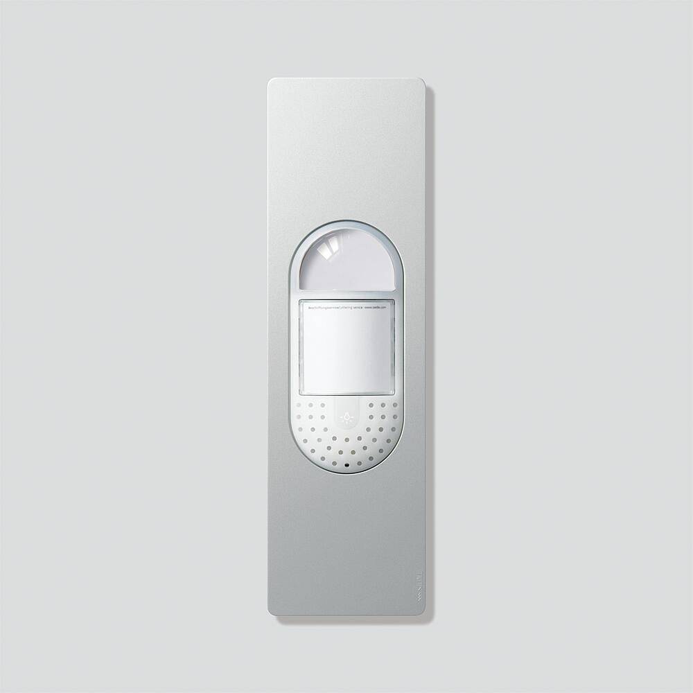 Eine schlanke, rechteckige silberne Türklingel mit einem kreisförmigen Knopf und kleinen Lautsprecherlöchern darunter, die für moderne Hauseingänge konzipiert ist.