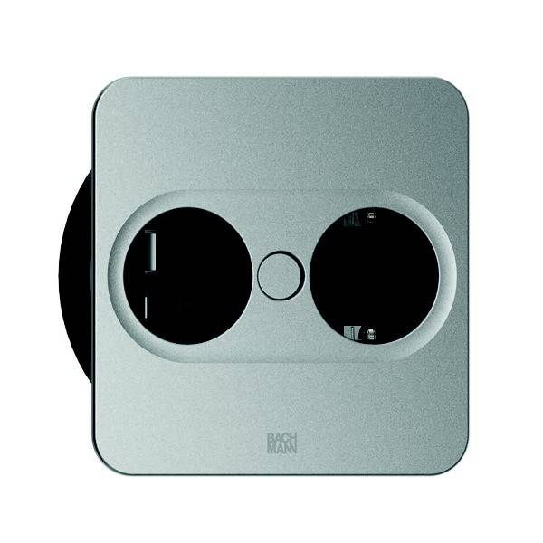 Eine silberne Steckdose mit Doppelsteckplatz in minimalistischem Design, mit zwei abgerundeten Steckeröffnungen, wird auf einer flachen Oberfläche gezeigt.