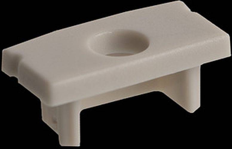 Eine kleine, rechteckige beige Plastikhalterung mit einem zentralen kreisförmigen Loch und zwei kurzen Beinen, möglicherweise zur Befestigung oder Unterstützung verwendet.