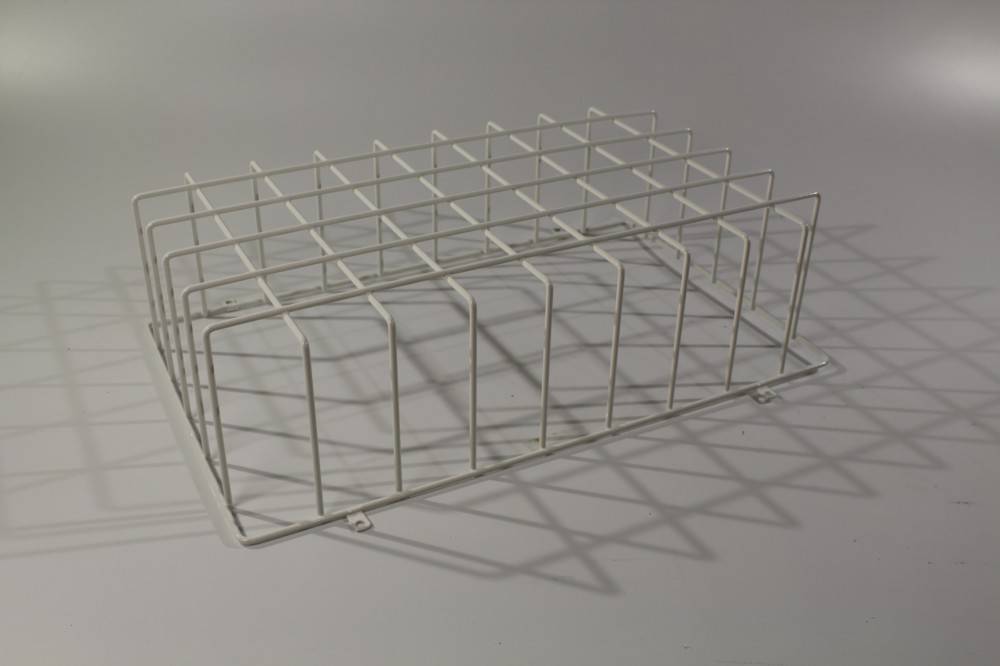 Ein Metalldrahtkorb mit rechteckigen Fächern, der Schatten auf eine helle Oberfläche wirft.