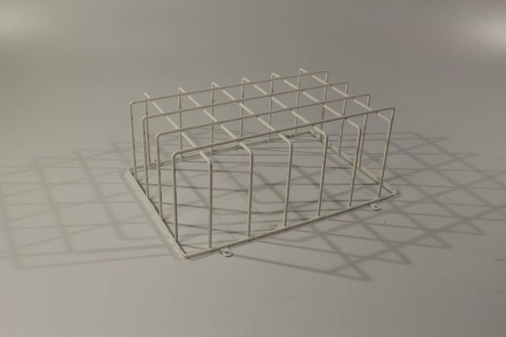 Ein weißer Metalldrahtständer mit Gitterstruktur, der Schatten auf einem hellgrauen Hintergrund wirft.