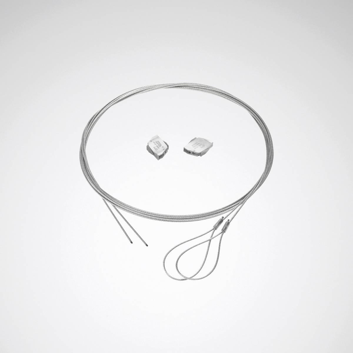 Ein kreisförmiges Drahtkabel ist neben zwei kleinen, transluzenten Kristallstücken auf einem weißen Hintergrund aufgewickelt.