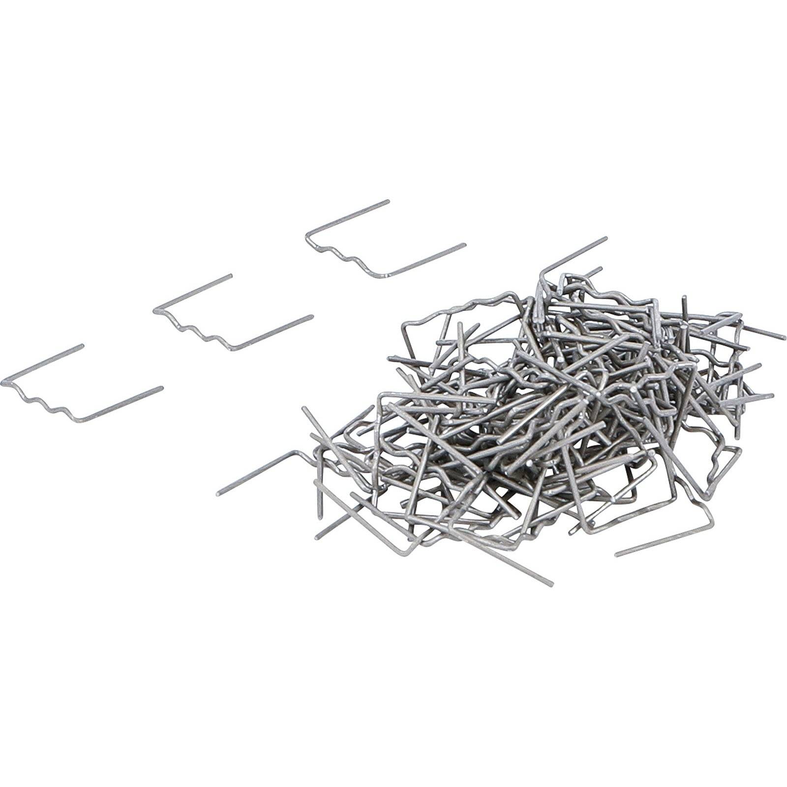 Ein Haufen U-förmiger Metallheringe, mit ein paar verstreut umherliegend, die zum Befestigen von Stoffen oder Netzen am Boden verwendet werden.