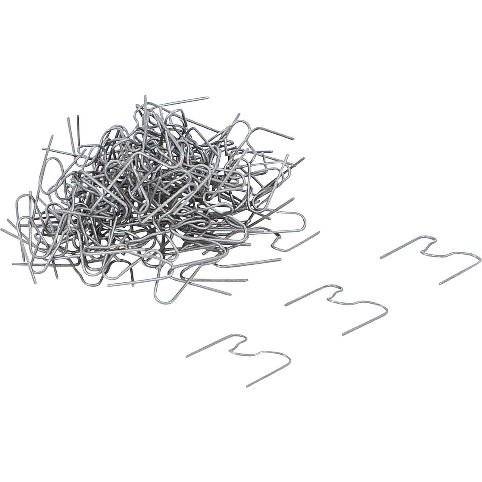 Ein Stapel silberner S-förmiger Metallklammern, mit einigen verstreut daneben, die für Zaunbau oder ähnliche Anwendungen verwendet werden.