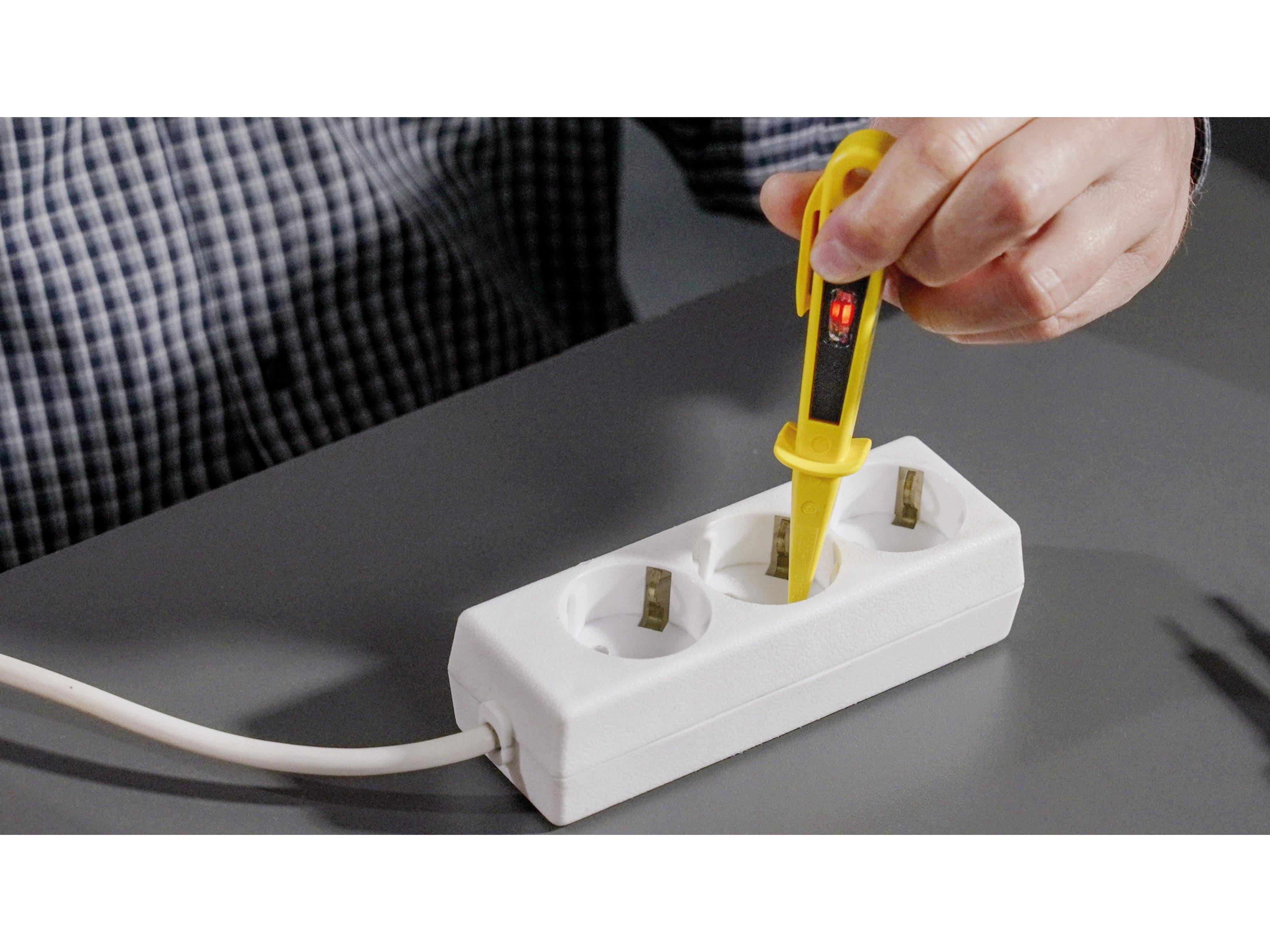 Eine Hand hält einen gelben Spannungsprüfer und überprüft eine Steckdosenleiste auf Stromspannung, angezeigt durch ein rotes Licht am Prüfer.