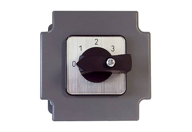 Ein Drehschalter mit vier Einstellungen, beschriftet von '0' bis '3' auf einer quadratischen Metallplatte vor einem grauen Hintergrund.