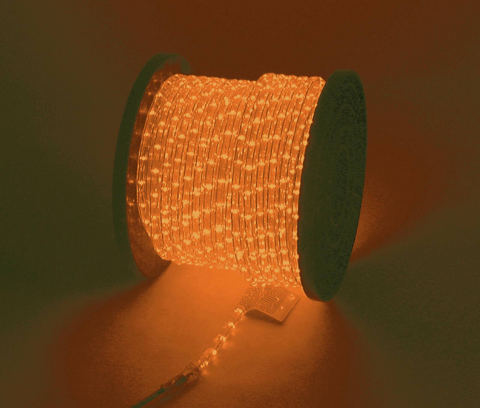 Eine Spule mit leuchtenden orangefarbenen LED-Streifenlichtern, teilweise abgewickelt und beleuchtet, vor dunklem Hintergrund.