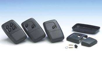 Drei schwarze elektronische Fernbedienungen mit Tasten werden auf einer hellen Oberfläche angezeigt. Zerlegte Teile und kleine Komponenten sind daneben angebracht.