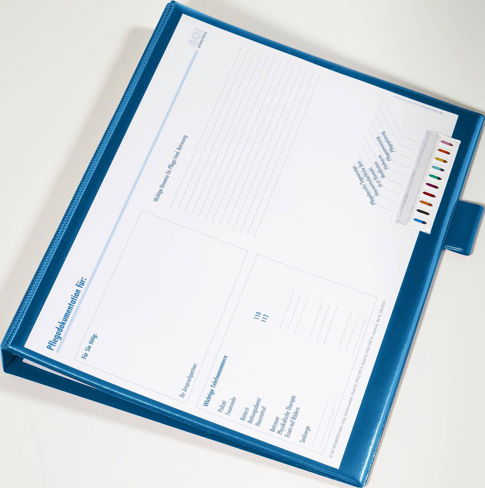 Ein blauer Ordner, aufgeschlagen auf einer Seite mit 