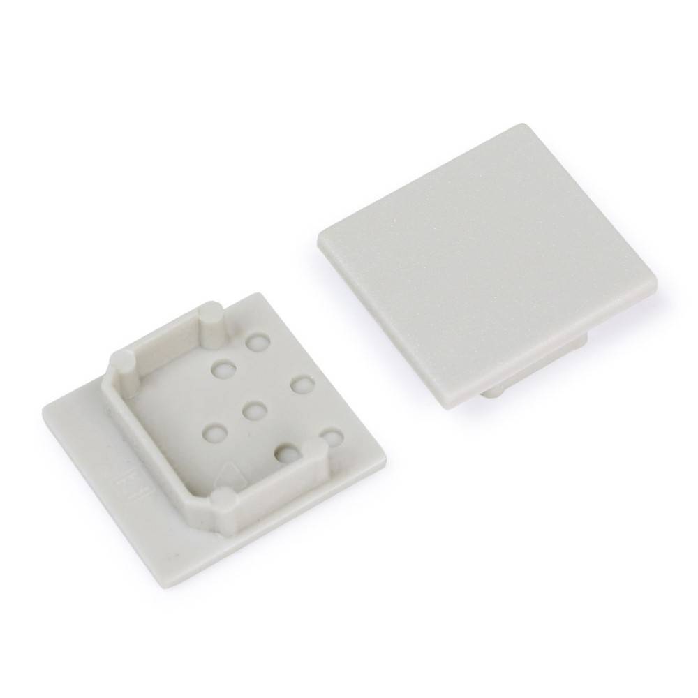 Zwei quadratische, beige Kunststoffkomponenten: eine mit Gittermuster und erhobenen Kanten und die andere flach. Geeignet für Strukturmontage oder Design.