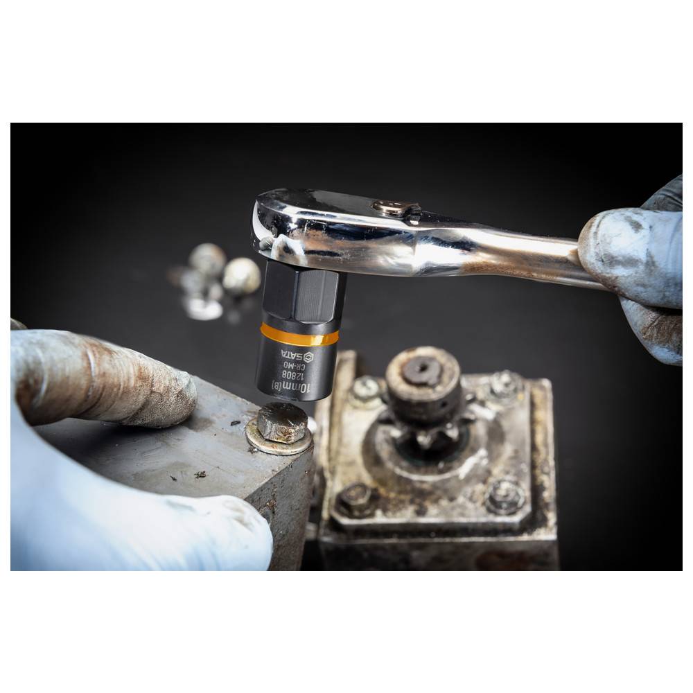 Ein Steckschlüssel wird verwendet, um eine Mutter an einem mechanischen Gerät festzuziehen, während eine behandschuhte Hand das Werkzeug hält, vor einem dunklen Hintergrund.