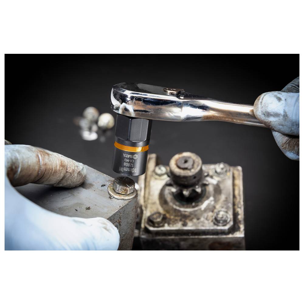 Eine Person mit Handschuhen verwendet einen Ratschenschlüssel mit einer Stecknuss, um eine Schraube an einem Metallteil einer Maschine festzuziehen, was eine mechanische Reparatur zeigt.