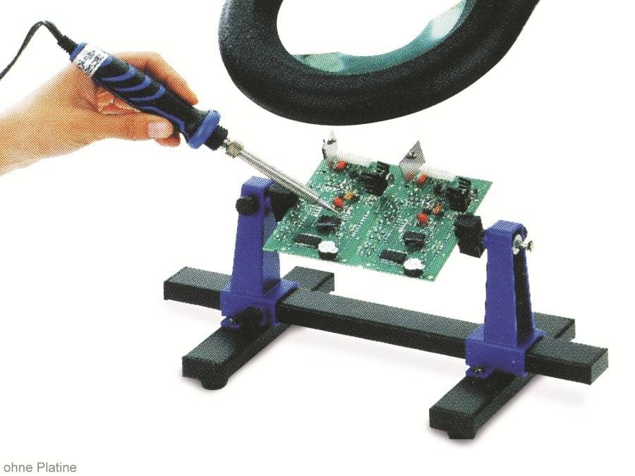 Eine Hand benutzt einen Schraubendreher, um eine von einer Klemme gehaltene Platine zu justieren, mit einer Lupe oben für detaillierte Arbeiten.