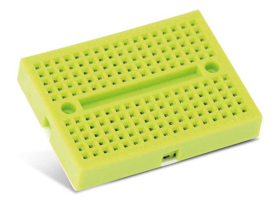 Ein kleines grünes Steckbrett ohne Löten mit zahlreichen Löchern für elektronische Prototypenentwicklung.