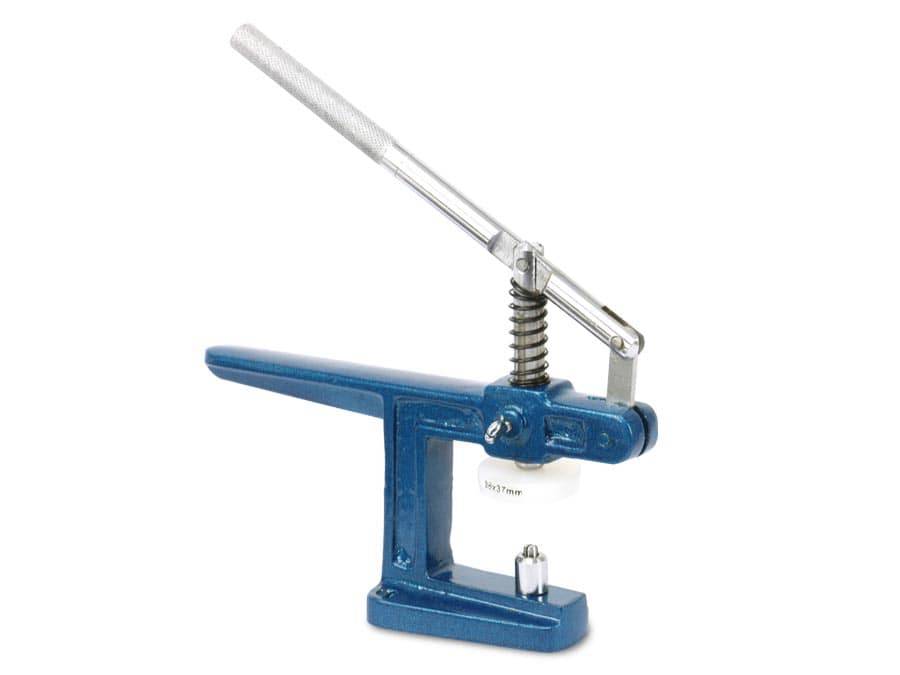 Eine blaue tragbare Prägemaschine mit langem silbernem Griff und Federmechanismus, die zum Anbringen von Druckknöpfen oder Knöpfen auf Stoff verwendet wird.