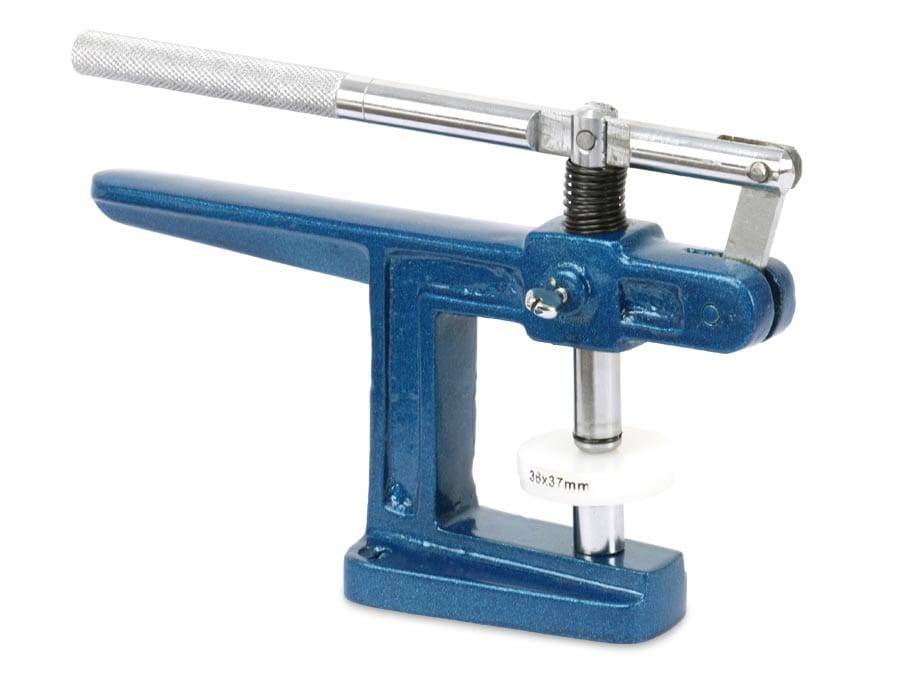 Eine blaue Metallknopfpresse mit einem Hebel und einem weißen Würfel, die zum Zusammensetzen von Knöpfen oder Stiften verwendet wird.