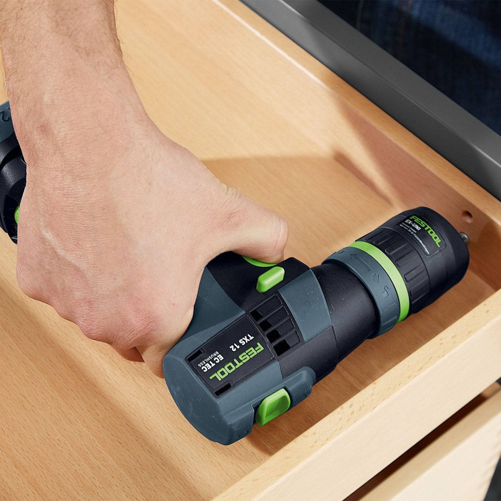 Eine Person, die einen Festool T 18+3 Akku-Bohrer an einem Holzpaneel verwendet, demonstriert die ergonomische Gestaltung und Griffeignung des Werkzeugs.