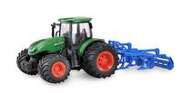 Grüner Spielzeugtraktor mit orangefarbenen Rädern zieht ein blaues Landwirtschaftsgerät auf weißem Hintergrund.